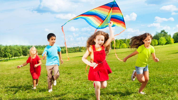 children flying rainbow colored kite blue sky