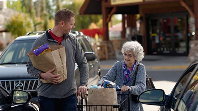 man helping an elderly woman with groceries